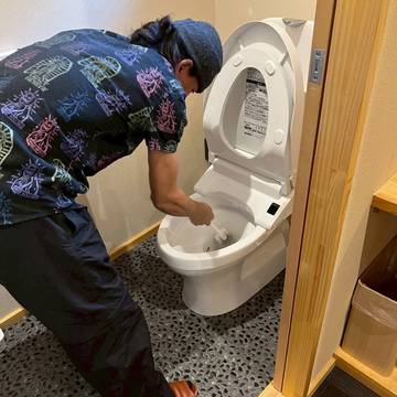 便器をブラシで洗浄するスタッフ