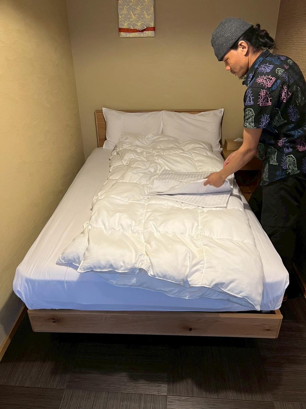 ベッドの角を整えるスタッフ